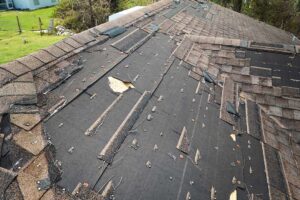 Worker installing new asphalt shingles on a residential roof under bright daylight with safety harness and tools visible.