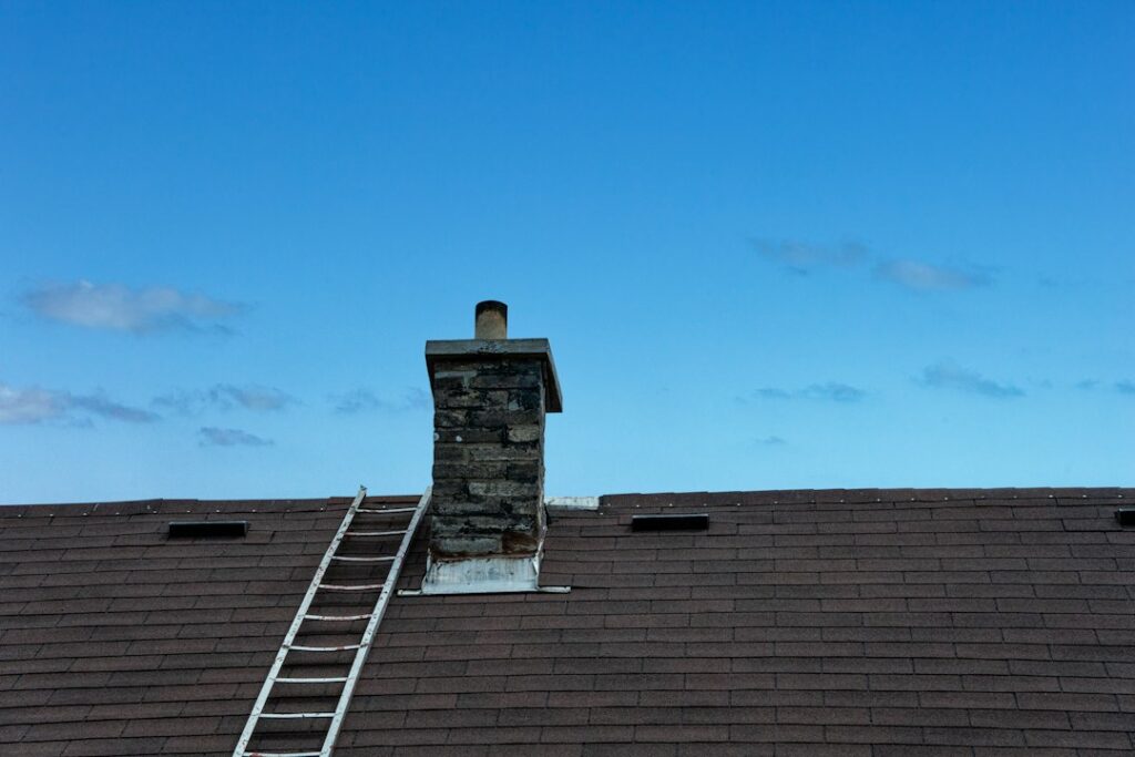 Homeowner examining roof shingles and flashing from the ground beside a residential house.